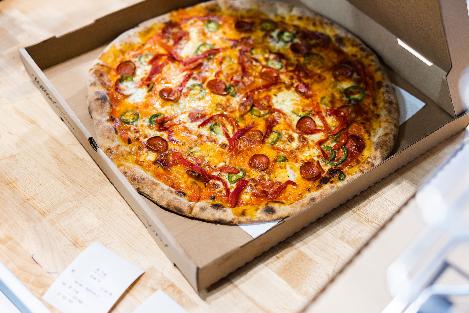 a freshly-made pizza thief pizza ready ready for delivery in a pizza box with the lid open