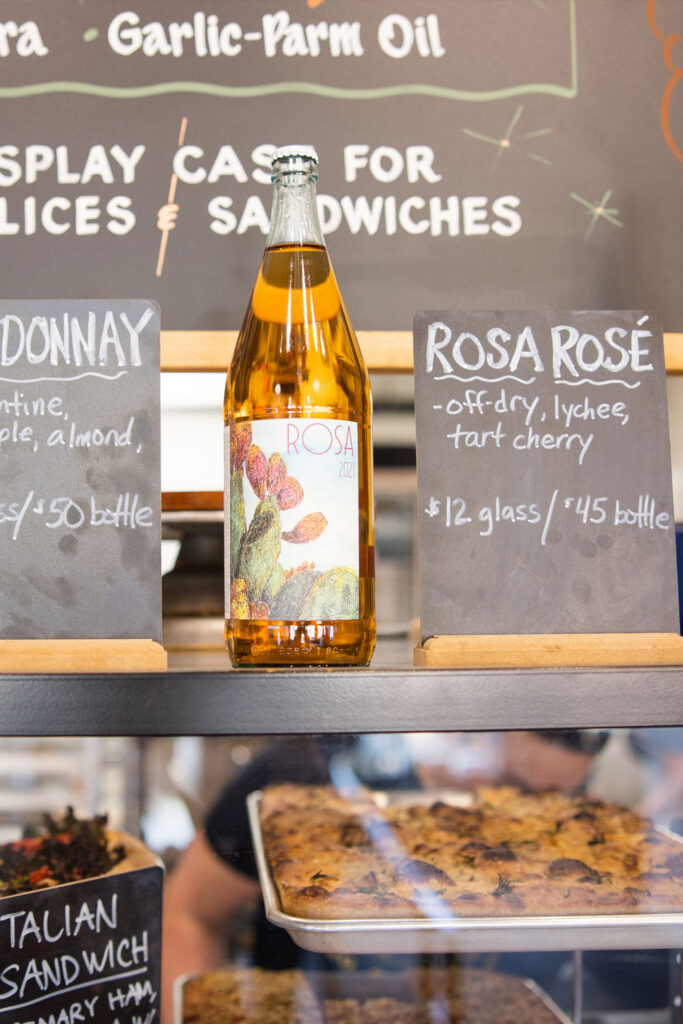 a bottle of rose on special sits atop the pastry case at pizza thief