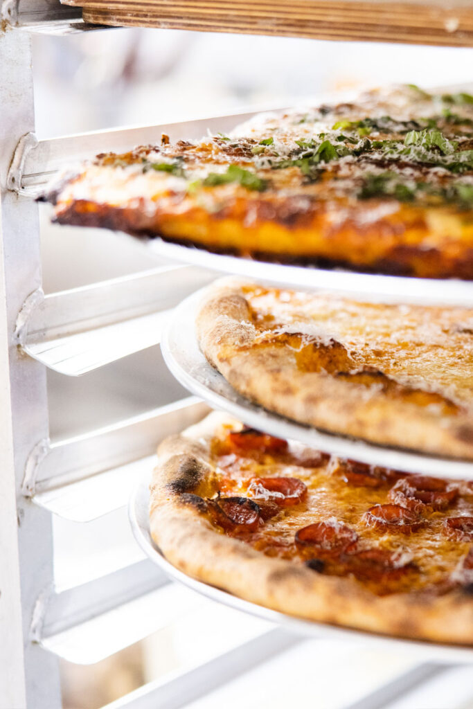 a trio of pizzas in the slice-to-go case at pizza thief
